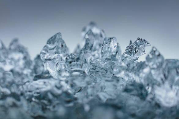 Eine Nahaufnahme von Wasser, das durch den Fotografen eingefroren wurde wie Eis vor einer blaugrauen Wand.
